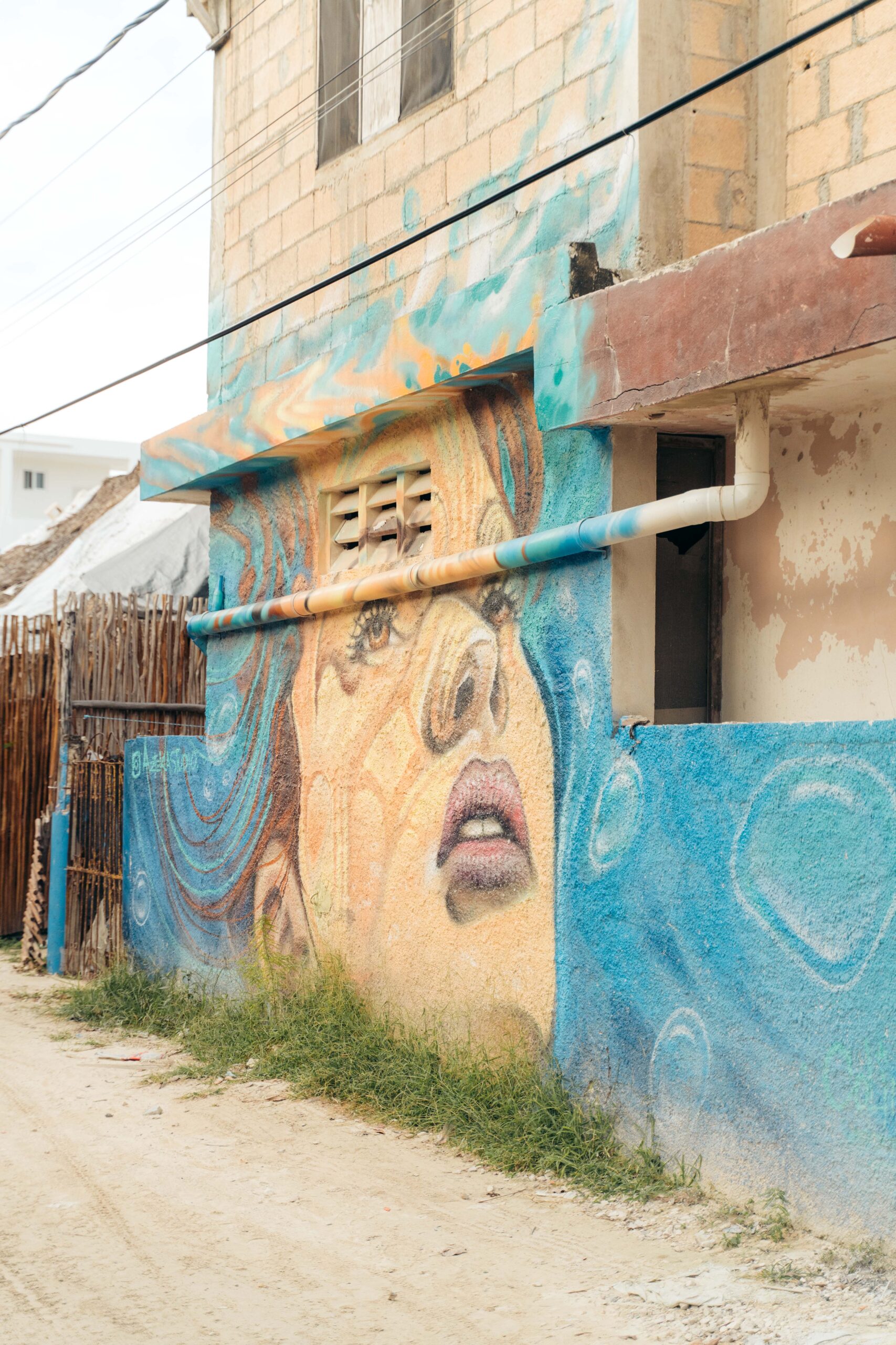 Street art of a woman with flowing hair in bold hues on Calle Carito, Holbox Island.