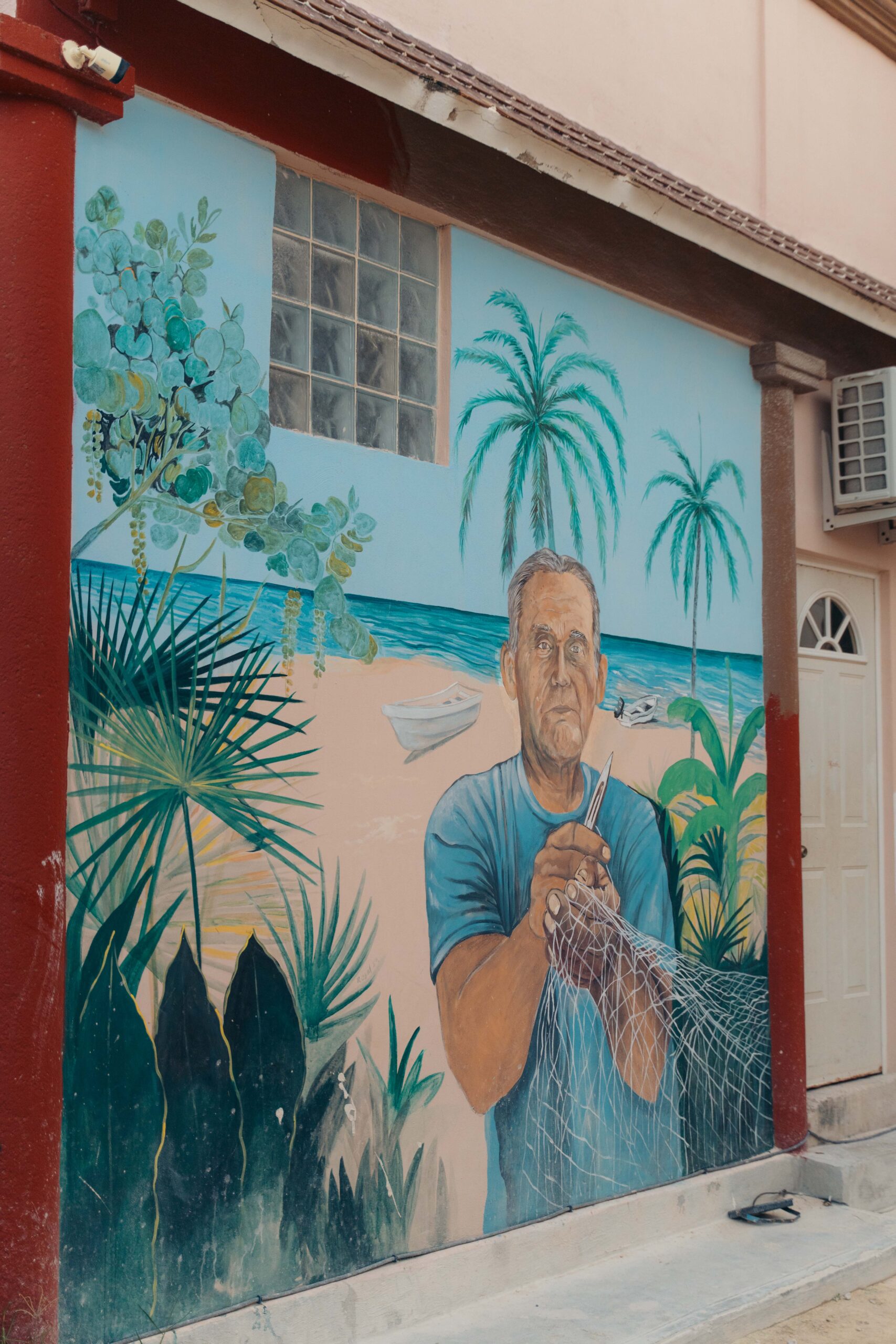 Mural of a fisherman holding a net, showcasing traditional fishing practices, located on Calle Carito in Holbox Island.